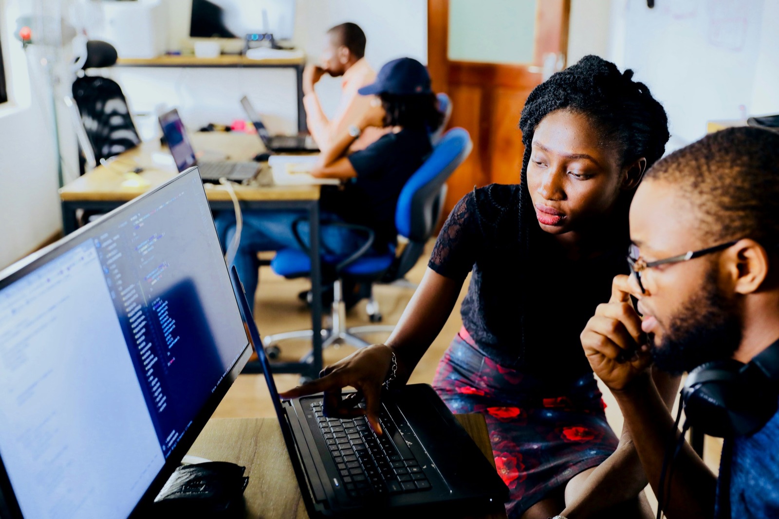 Two engineers pair-programming at a shared screen in a Lagos workspace