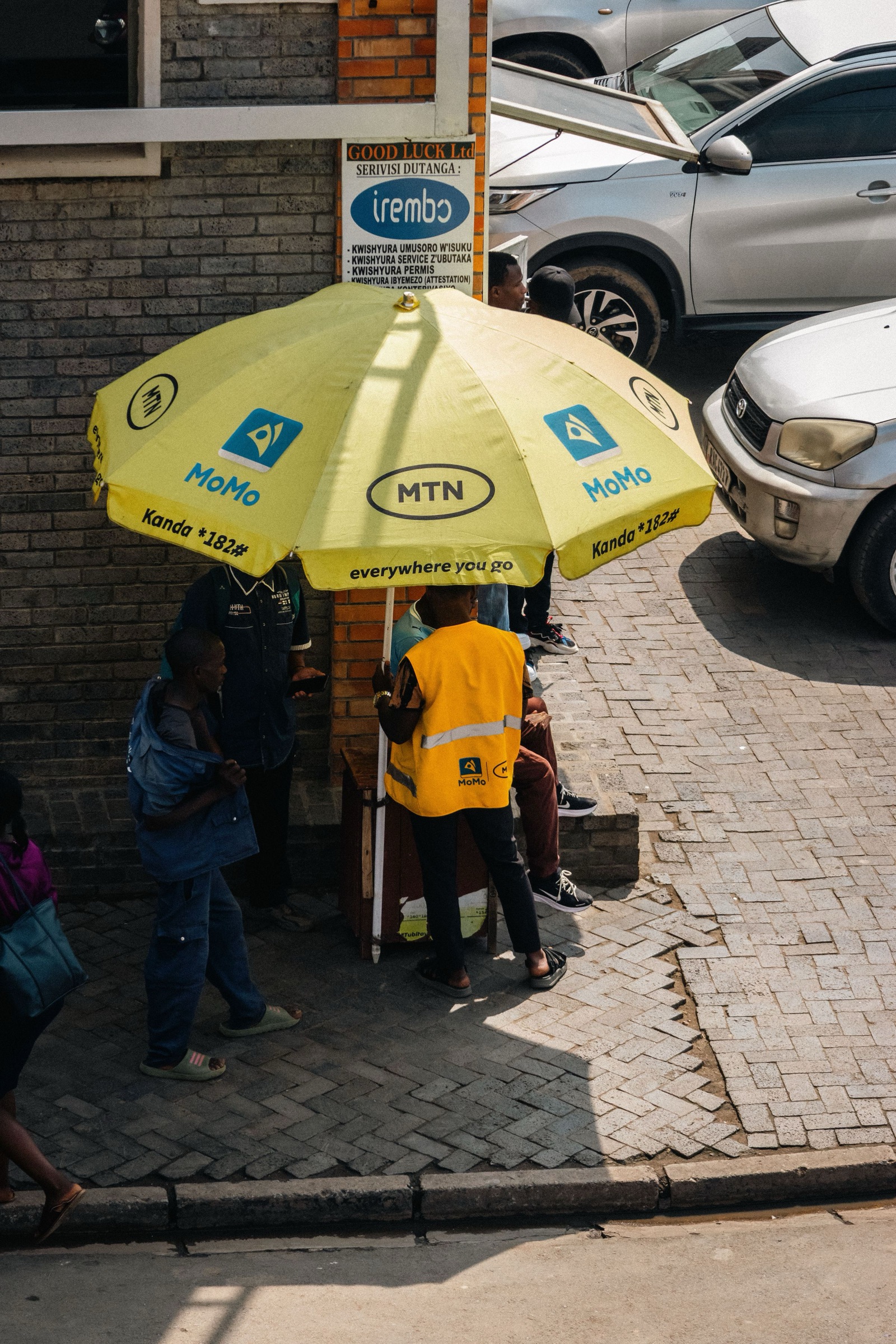 A mobile-money agent serving customers under a yellow umbrella